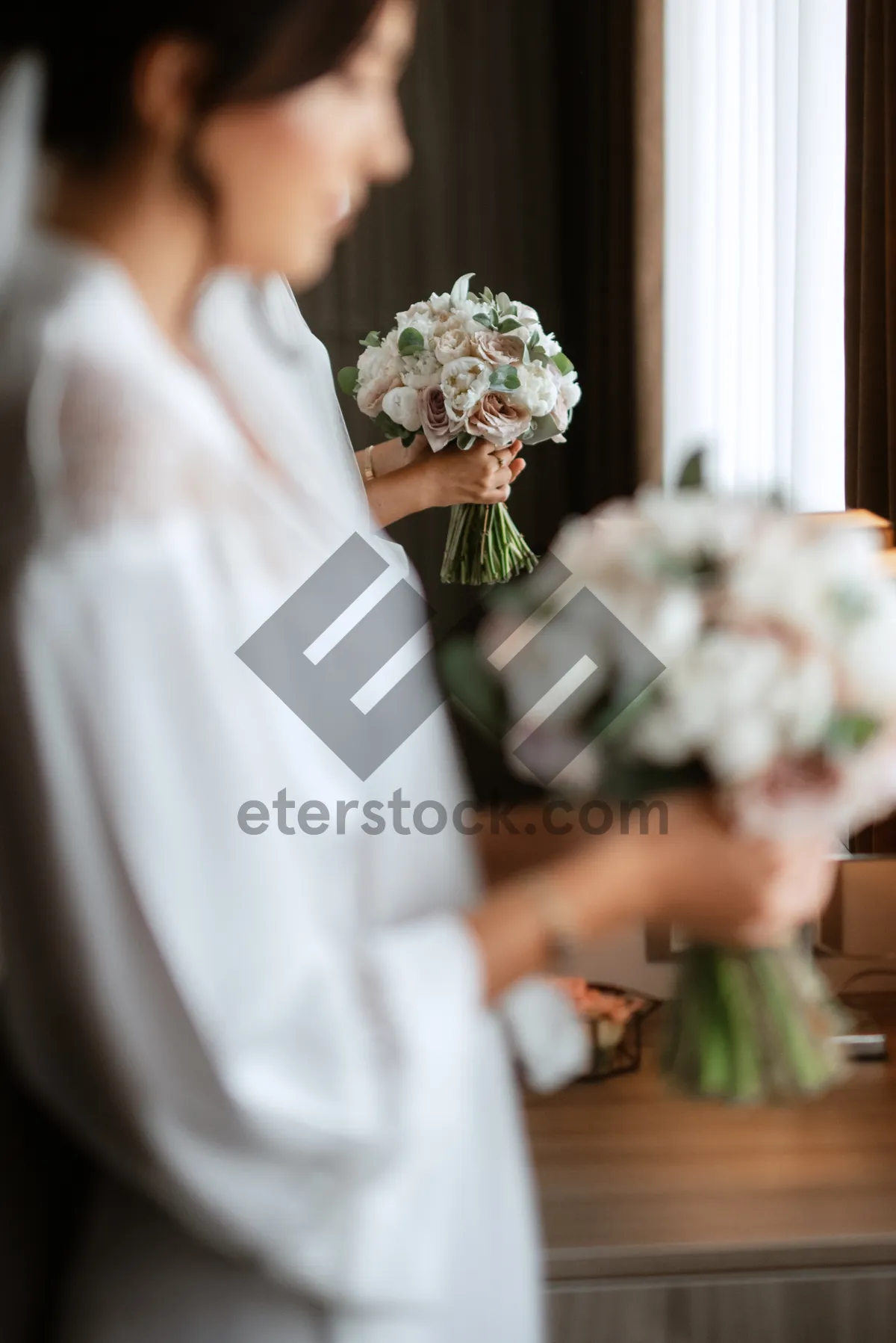 Picture of Happy newlywed couple with bouquet of roses at wedding.