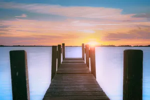 Tropical sunset over beach with boat dock.