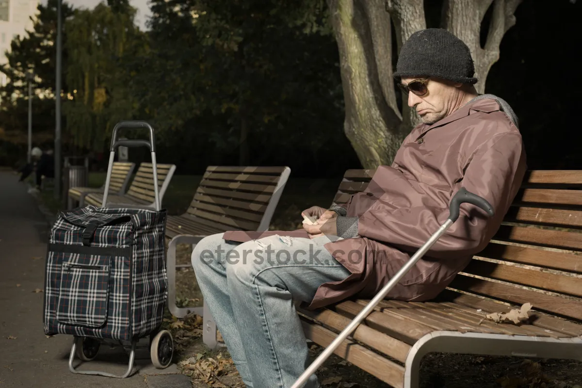 Picture of Male person sitting on park bench with crutch