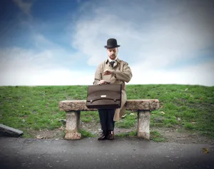 Man working on laptop at park bench outdoor.