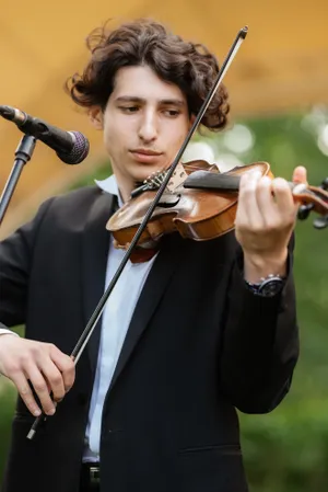 Attractive adult musician playing the violin with phone