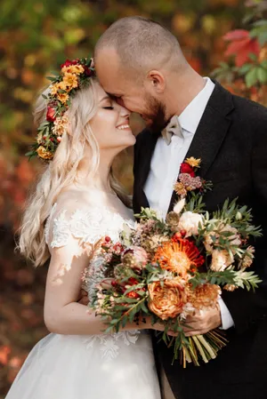 Happy couple celebrating wedding outdoors with flower bouquet