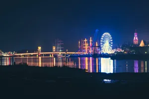 Modern city skyline at night with bridge reflection.