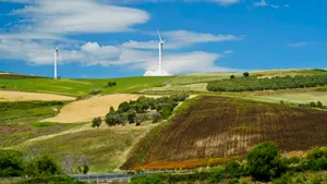 Meandering Clouds Over Rolling Green Hills and Wind Turbines