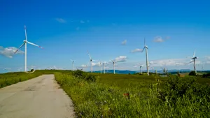 Sunny countryside landscape with wind turbine and clouds