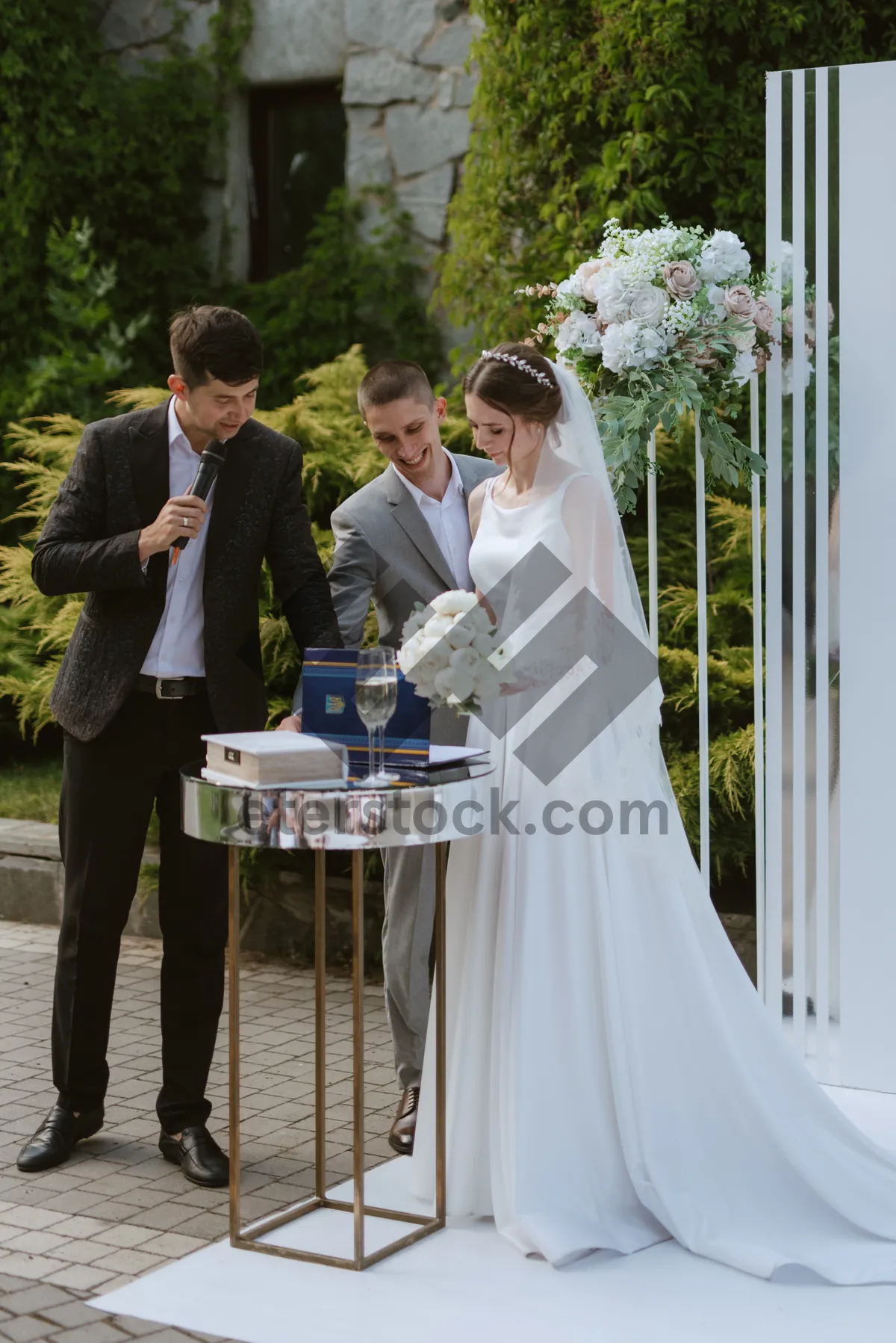 Picture of Happy wedding couple celebrating outdoors with a flower bouquet.