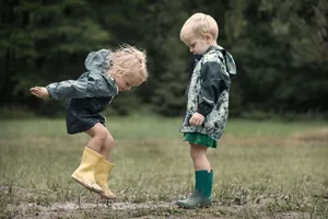 Happy blond boy playing with rugby ball in park.