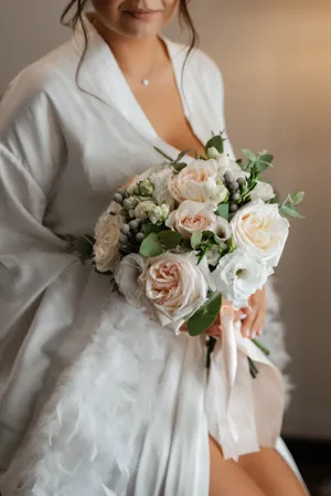 Happy newlywed couple holding rose bouquet on wedding day.