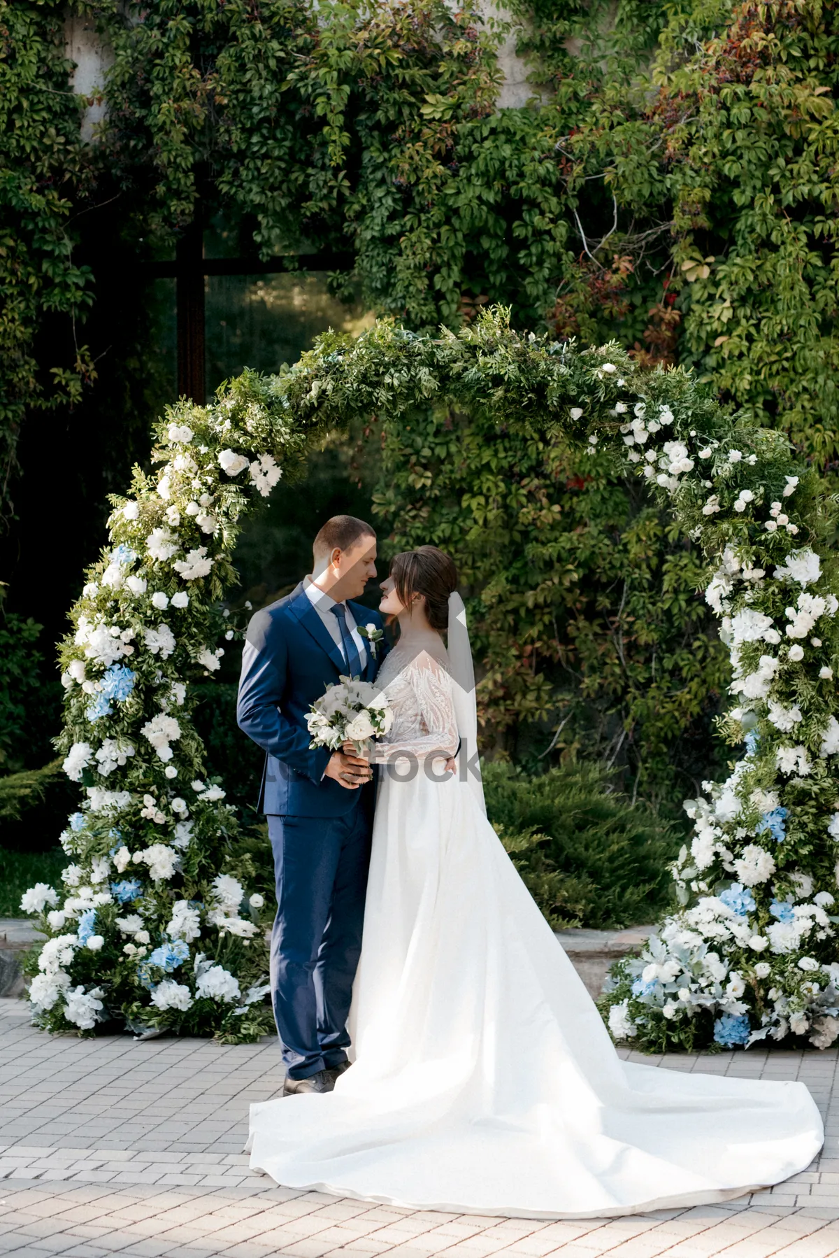 Picture of Happy couple celebrating wedding with flower bouquet outdoors.