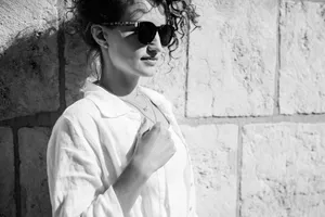 Smiling brunette model wearing stylish sunglasses in studio