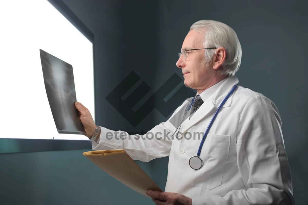 Picture of Happy male doctor working on laptop in hospital office