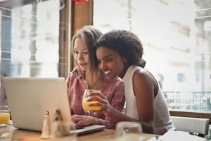 Happy couple dining at restaurant with laptop