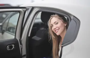 Attractive adult driving a car with happy smile.