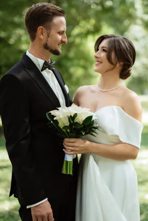 Happy couple celebrating wedding outdoors with bouquet.