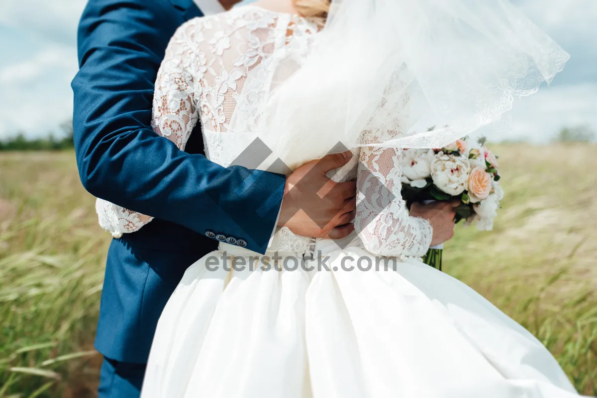 Picture of Happy couple in wedding attire holding bouquet of flowers