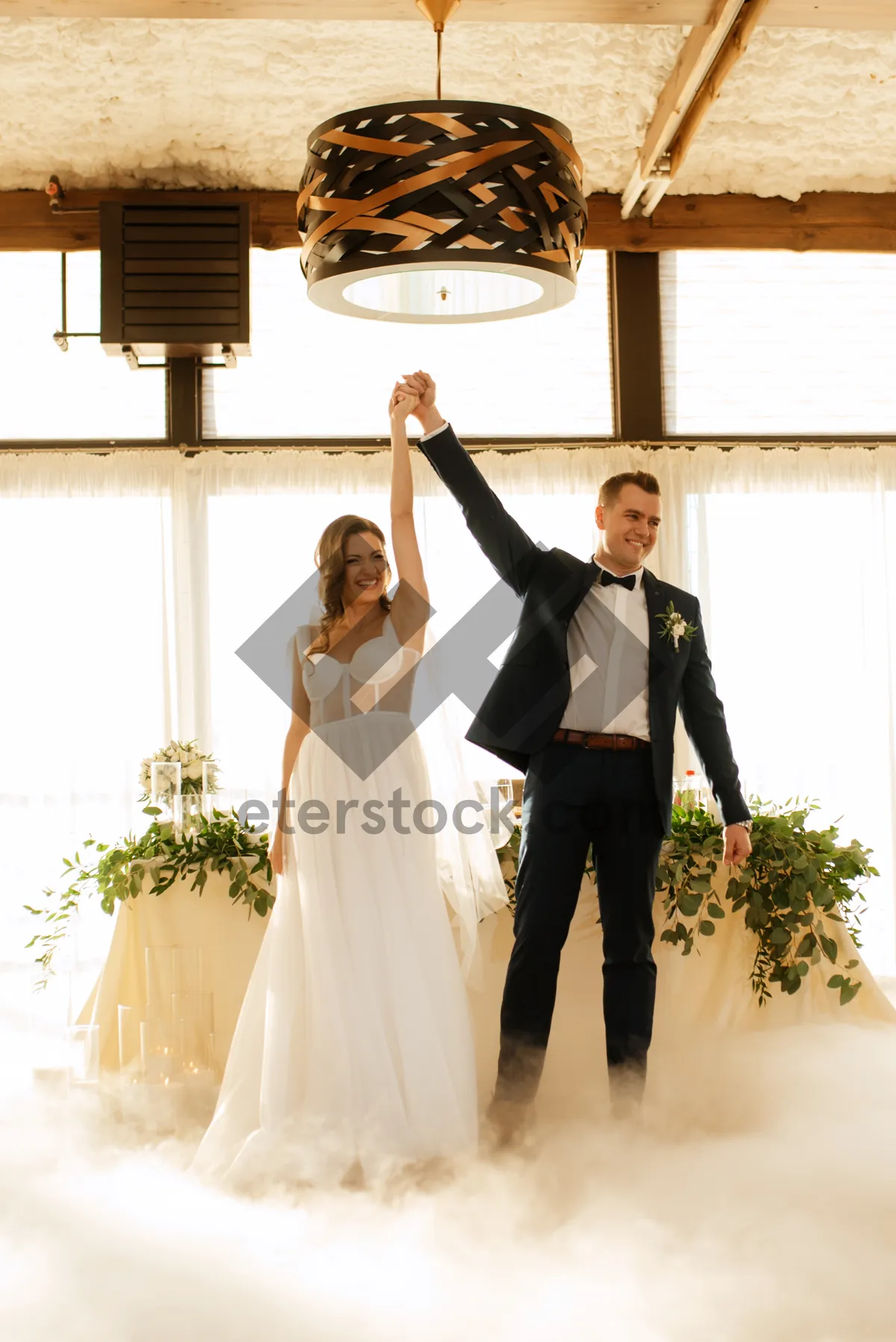 Picture of Happy groom kissing bride with bouquet at wedding ceremony