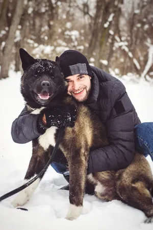 Happy man with shepherd dog sledding in snowy winter.