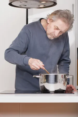 Happy male chef cooking in kitchen with crock pot