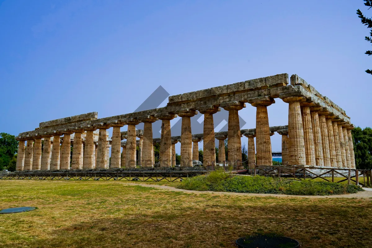 Picture of Roman viaduct over ancient city ruins under blue sky.