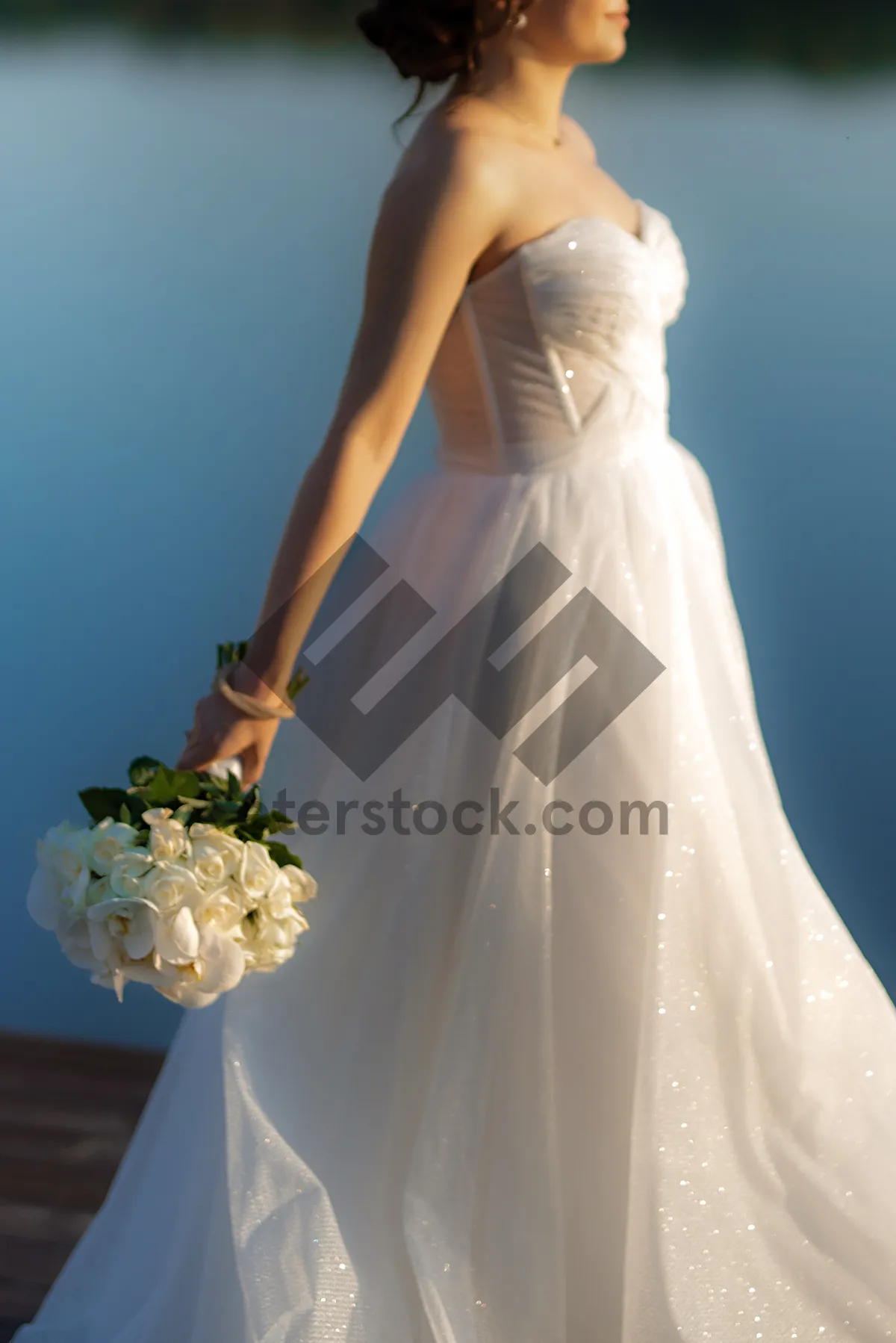 Picture of Happy newlywed couple in wedding attire holding flowers