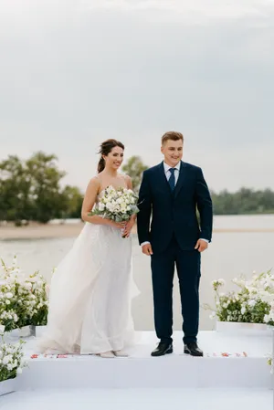 Happy couple celebrating wedding day outdoors with flowers and smiles.