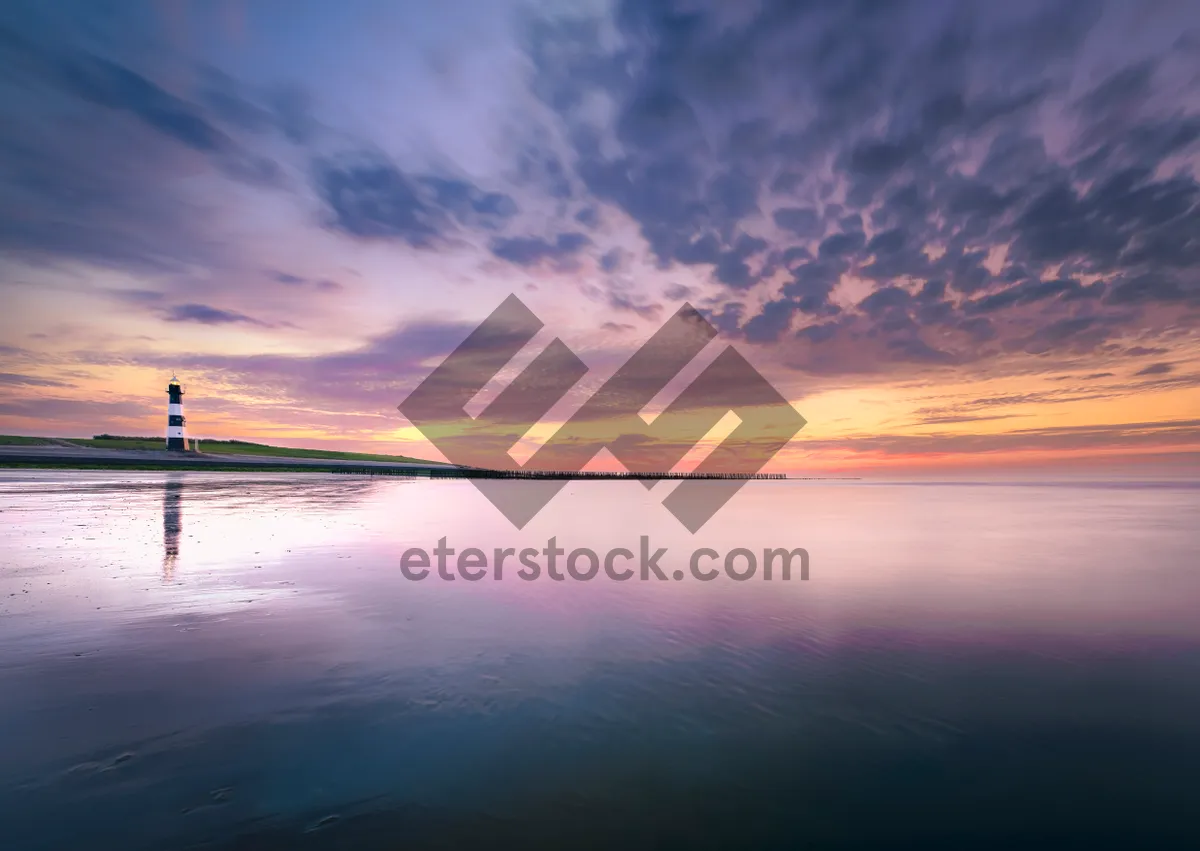Picture of Orange sunset over tranquil ocean waves on beach shore.