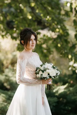 Happy couple celebrating wedding outdoors with flower bouquet