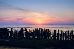 Sunset skyline over coastal city with pier.