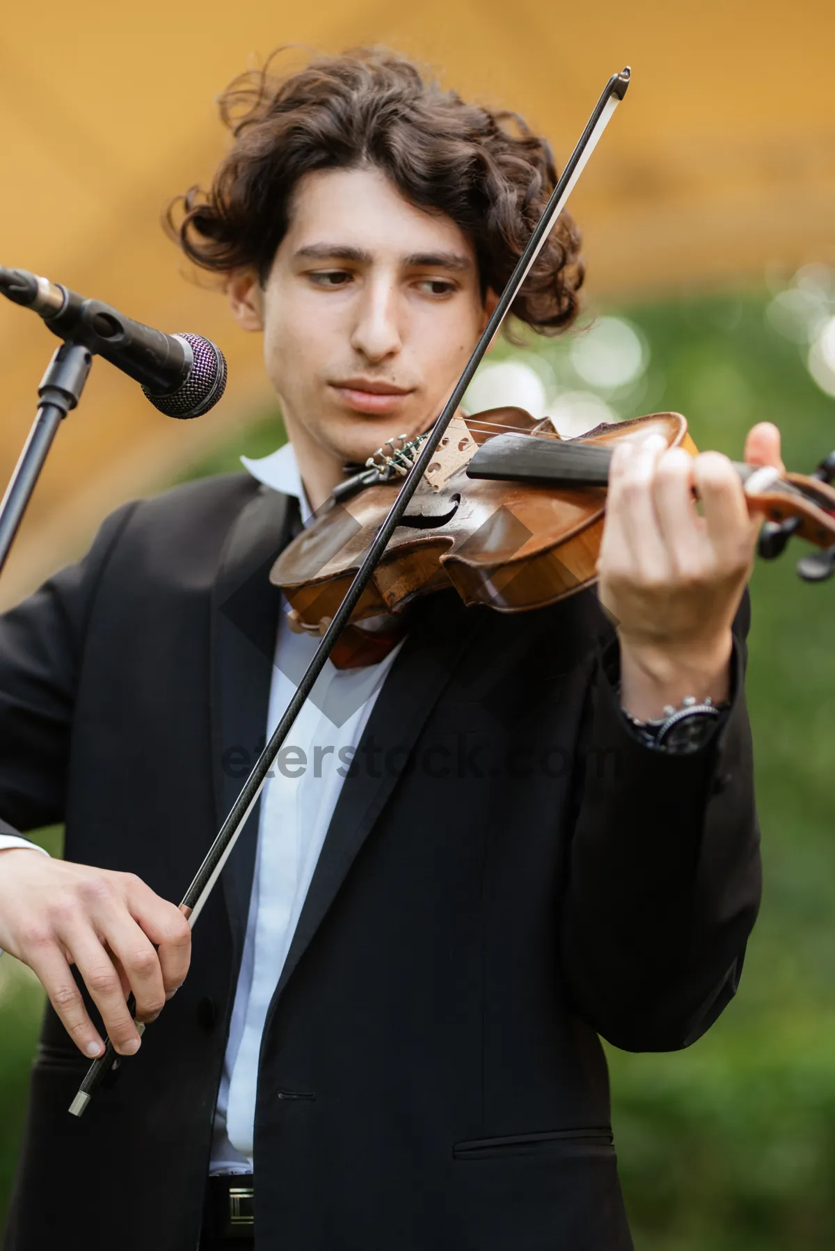 Picture of Attractive adult musician playing the violin with phone