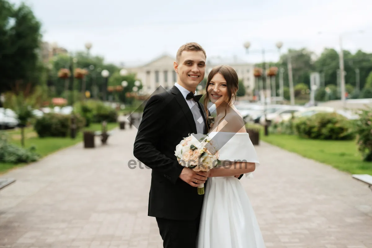 Picture of Happy groom and bride with bouquet outdoors