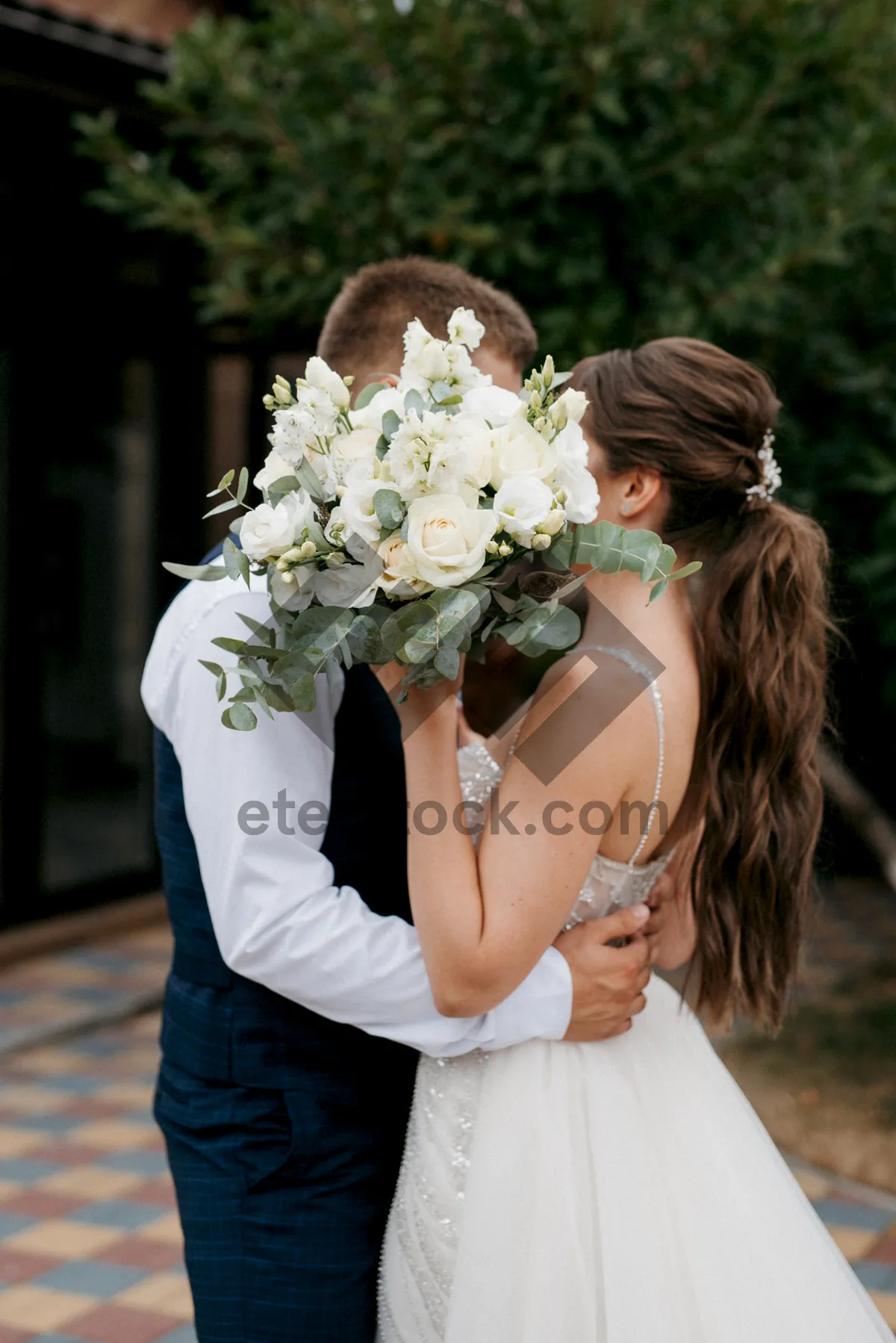 Picture of Smiling wedding couple outdoors with flower bouquet