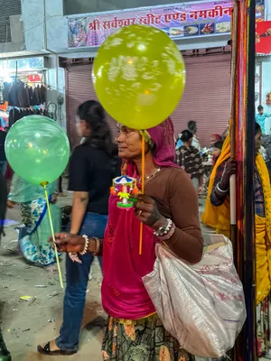 Smiling seller with colorful balloons at market