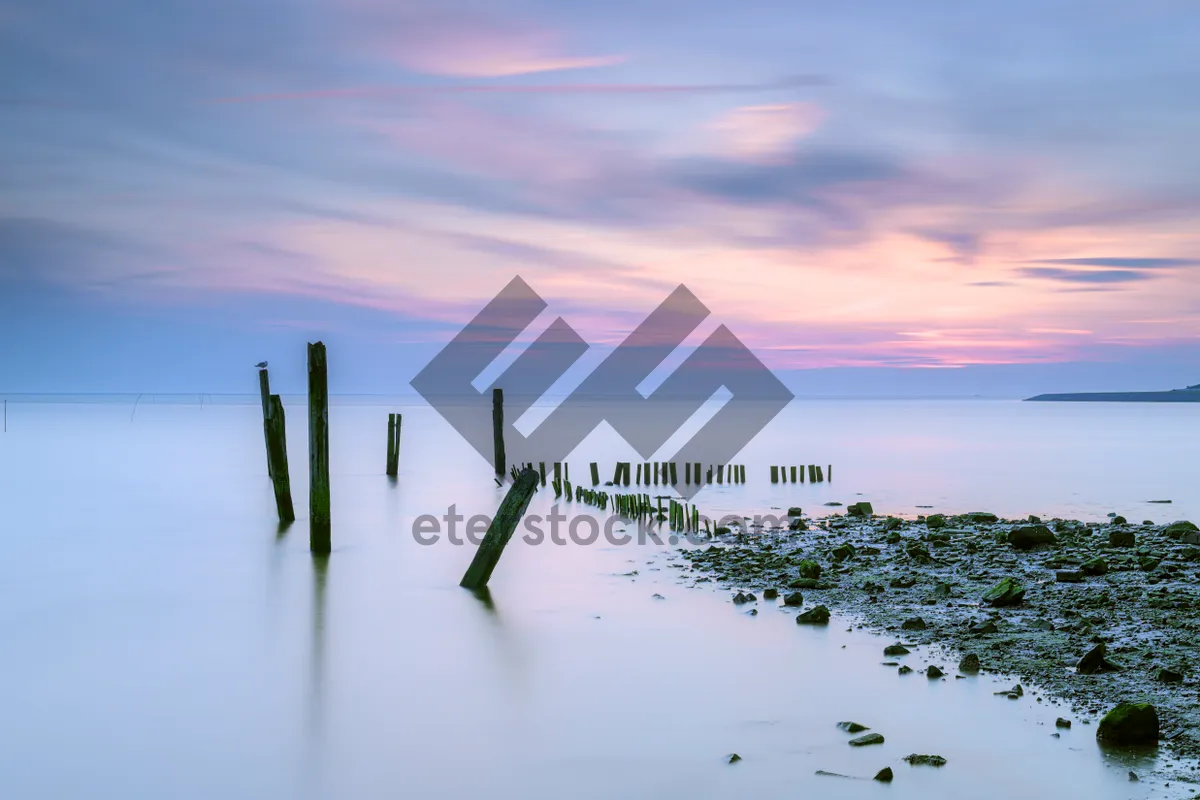 Picture of Beach silhouette at sunset over calm ocean.