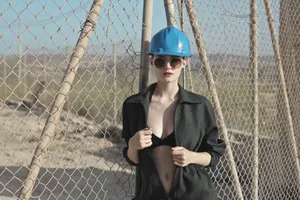 Attractive adult male at baseball batting cage fence.