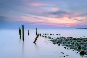 Sunset silhouette over tranquil beach shoreline.