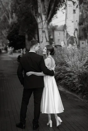 Happy groom and bride in wedding gown holding bouquet