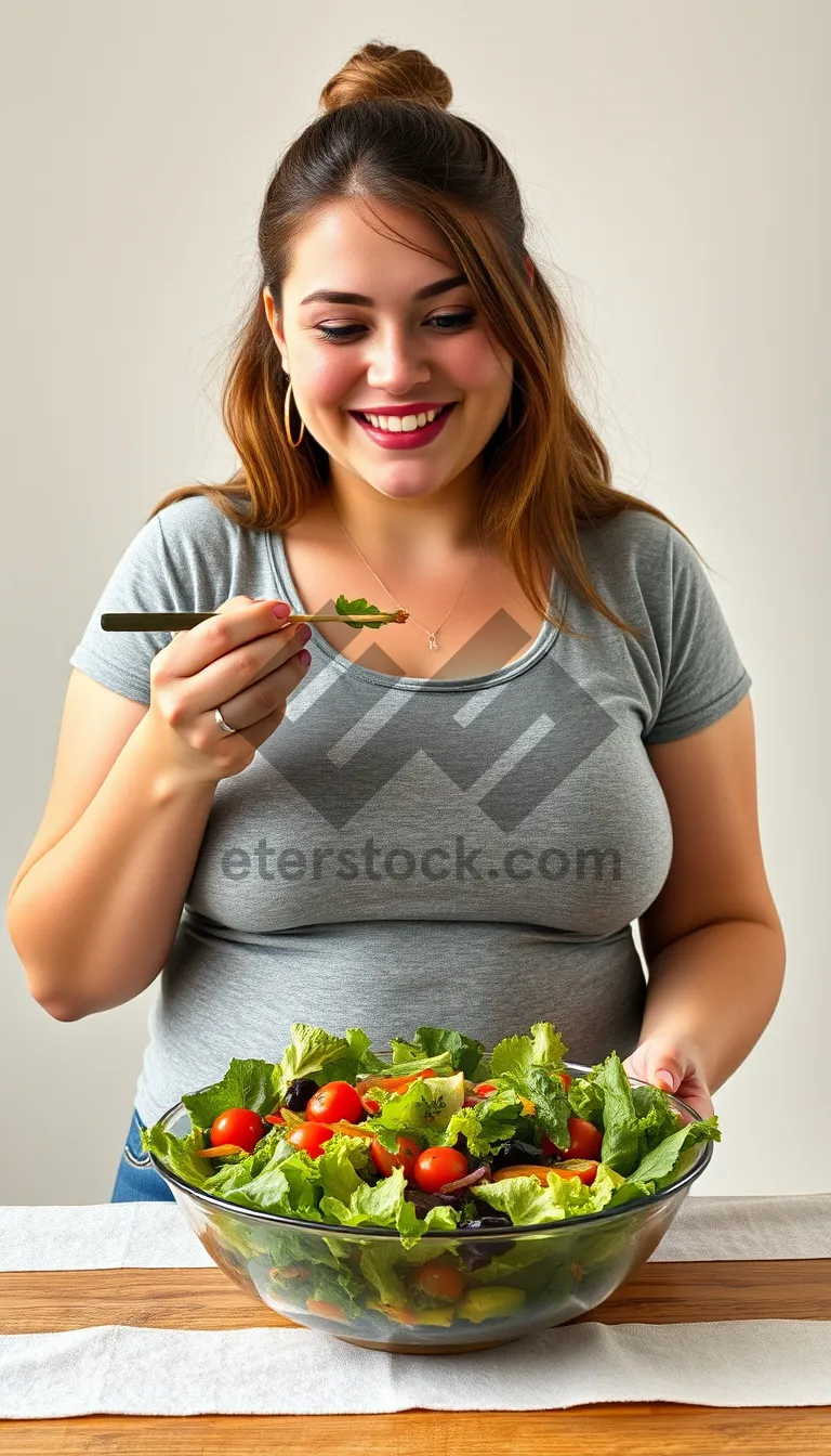 Picture of Happy woman holding a vegetable salad in kitchen