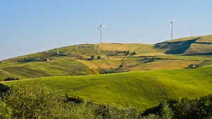 Summer rural landscape with wind turbine on hill.