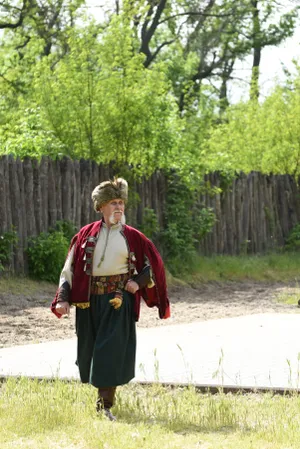 Person in cloak walking through outdoor forest park.