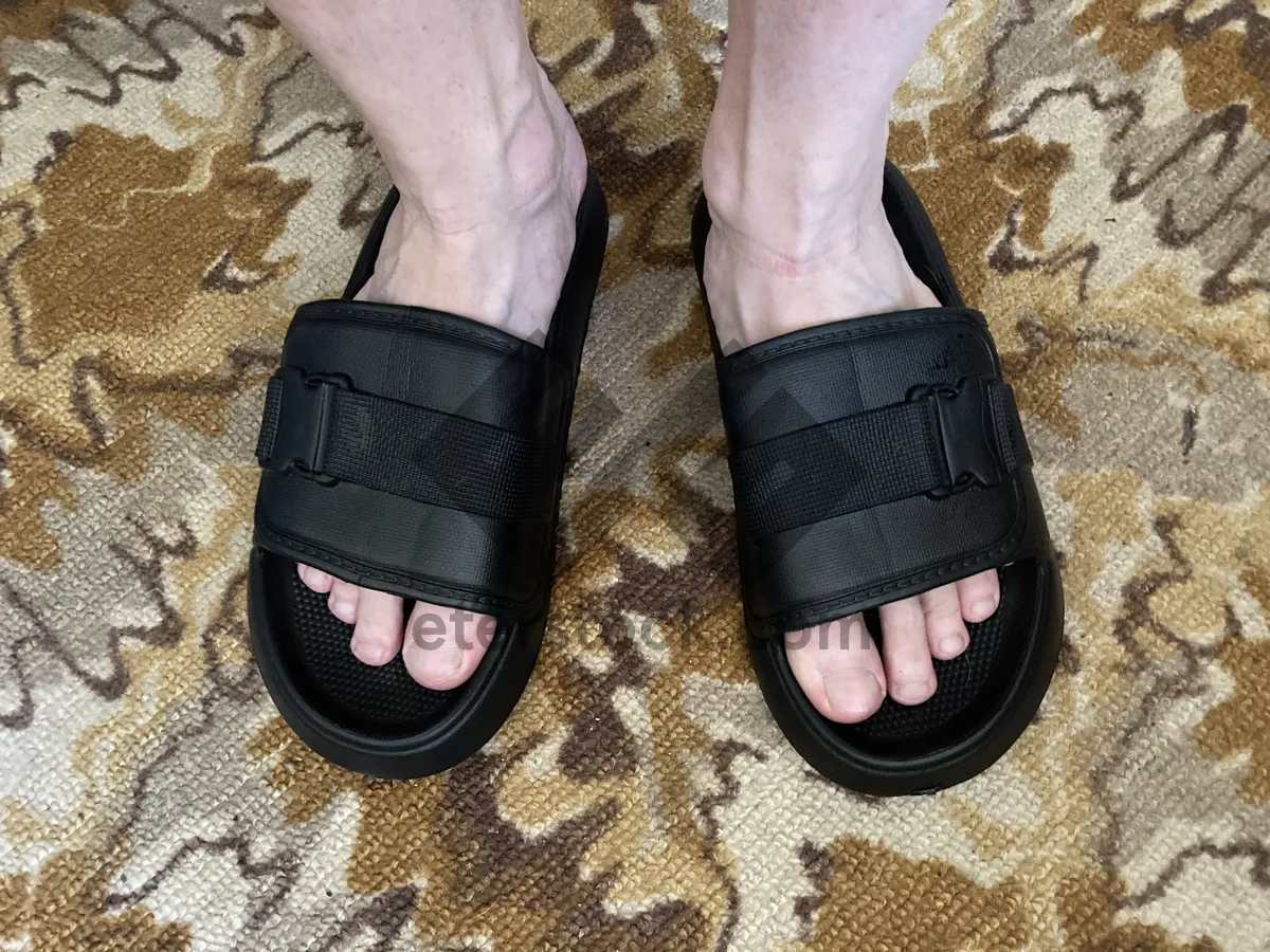 Picture of A man stands in black flip-flops on the carpet