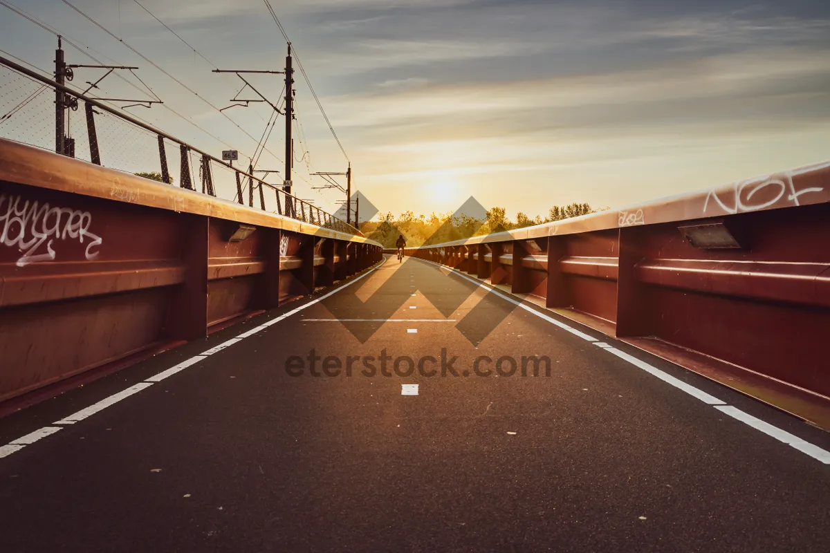 Picture of Suspension bridge connecting cityscape over river against blue sky.