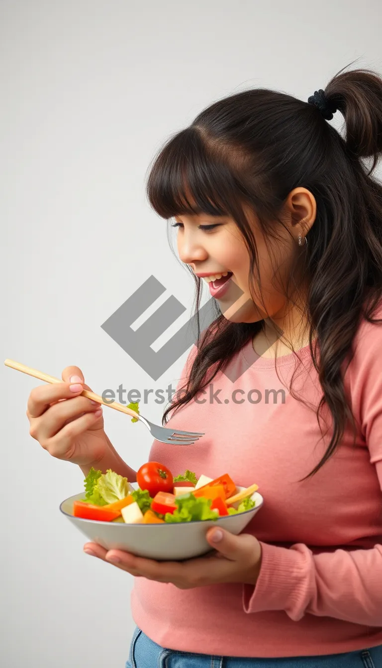 Picture of Happy woman preparing and eating healthy salad at home