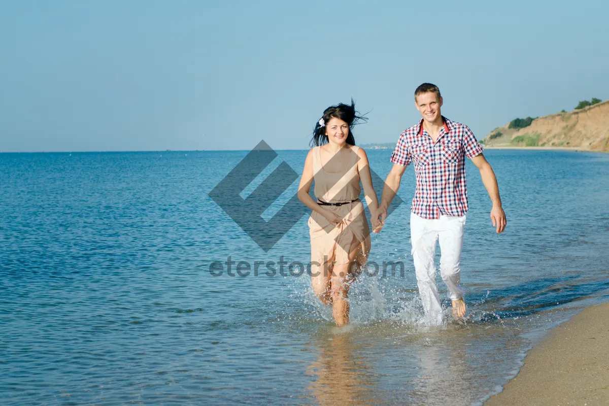 Picture of Happy couple walking on tropical beach shore in sarongs.