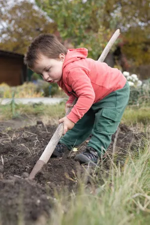 Happy Child Playing in Autumn Field with Rake.