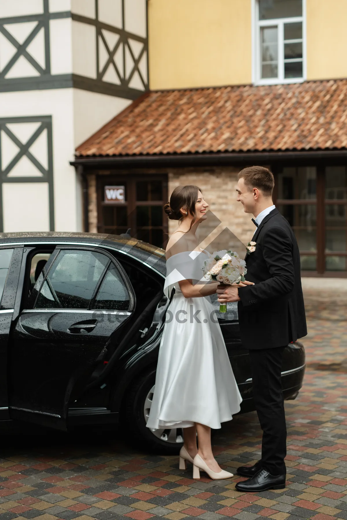 Picture of Happy newlywed couple smiling on wedding day with flower bouquet