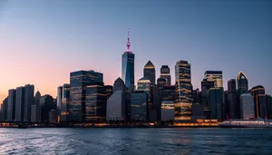 Modern city skyline at sunset with waterfront reflection.