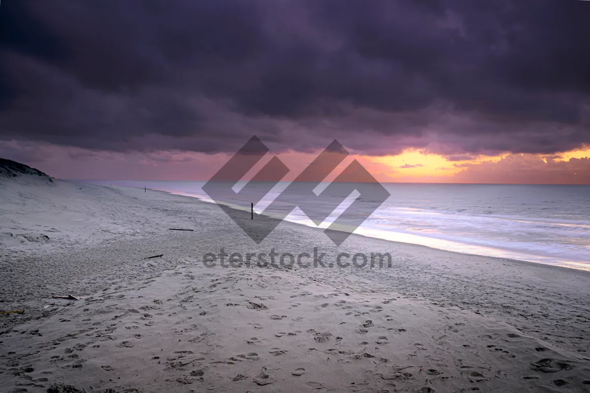 Picture of Tropical sunset over crystal blue waves on beach coast.