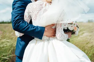 Happy couple in wedding attire holding bouquet of flowers