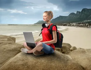 Happy businessman working on laptop at the beach.