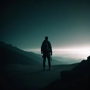 Man Hiking a Mountain at Sunset with Silhouette